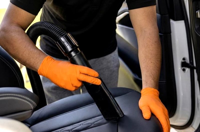 DShine technician vacuuming leather seat during quick detail mobile service — South Florida